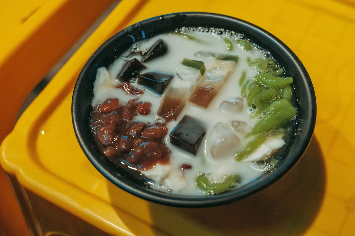 Asian jelly dessert with colorful jelly cubes, red beans and creamy milk